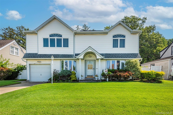 View of front of home featuring a garage, a front lawn, driveway, and roof with shingles