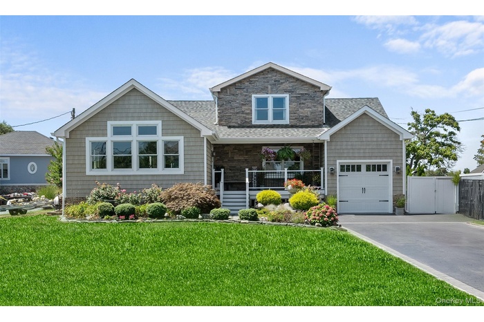 View of front of home featuring covered porch, stone siding, a front lawn, and driveway