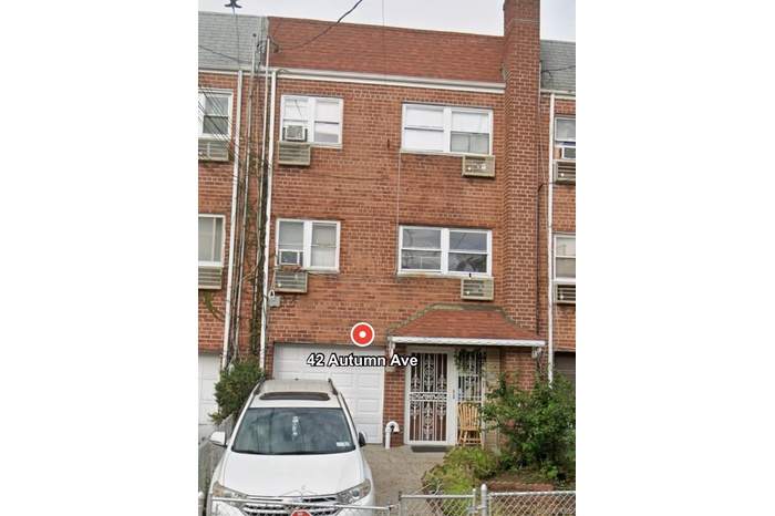 View of front facade featuring brick siding, a fenced front yard, and a garage