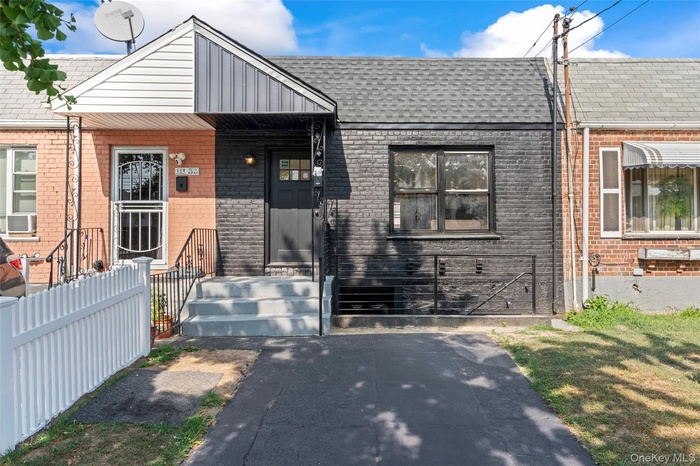 View of front of home featuring brick siding and roof with shingles