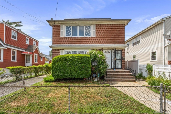 Traditional home featuring brick siding and a fenced front yard