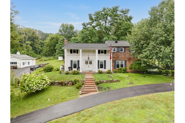 View of front of house featuring a chimney, a front yard, and brick siding