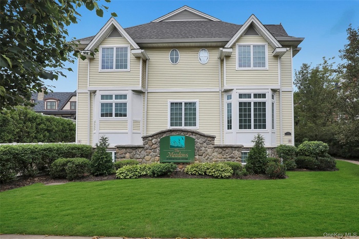 Back of property with a lawn, stone siding, and a shingled roof