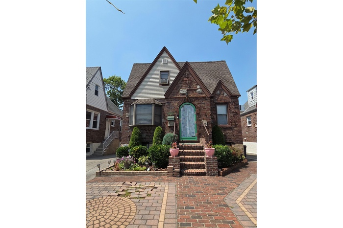 English style home with a shingled roof and brick siding