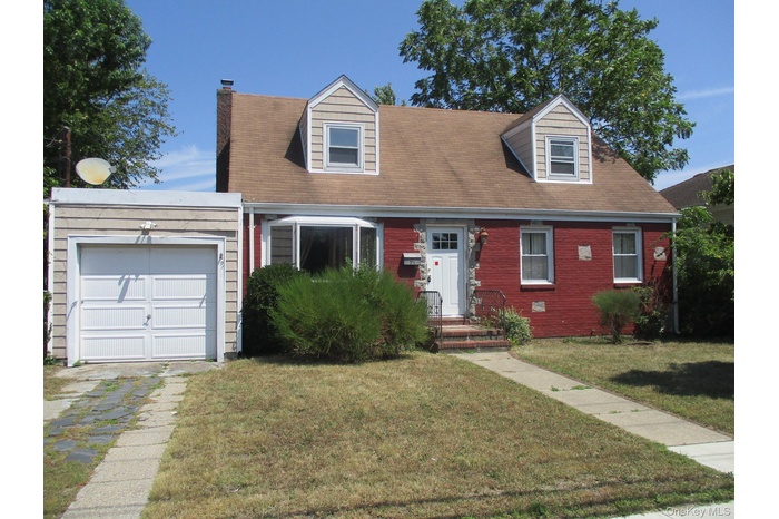 New england style home with a chimney, a garage, a front lawn, and a shingled roof