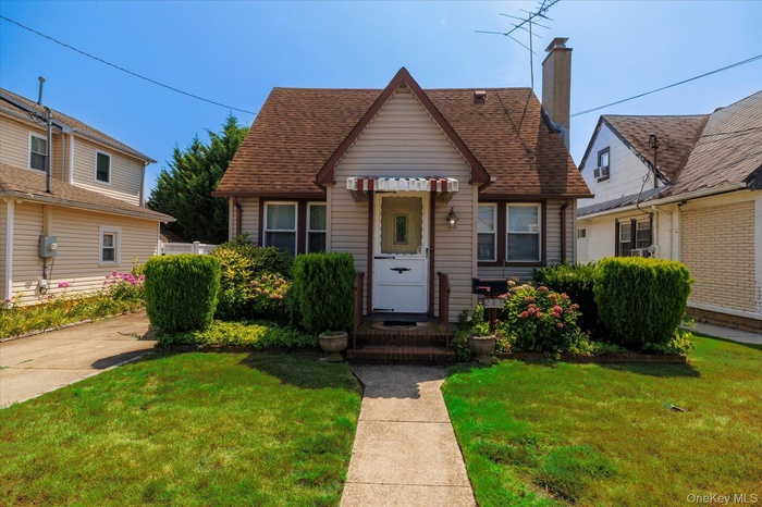 Bungalow-style home featuring a front lawn, roof with shingles, and a chimney