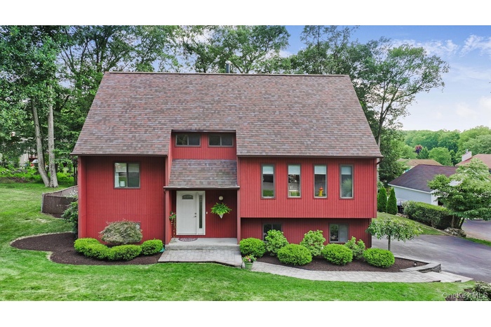 View of front of property with a shingled roof and a front lawn