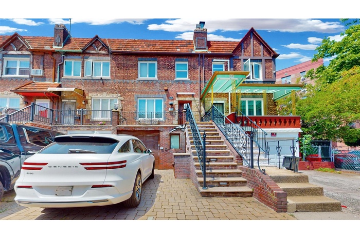 Multi unit property with brick siding, a chimney, stairway, and an attached garage