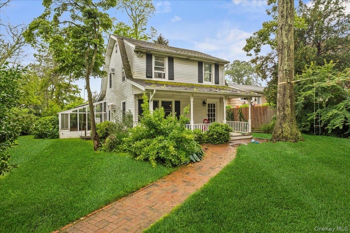 Farmhouse-style home with a front lawn and covered porch