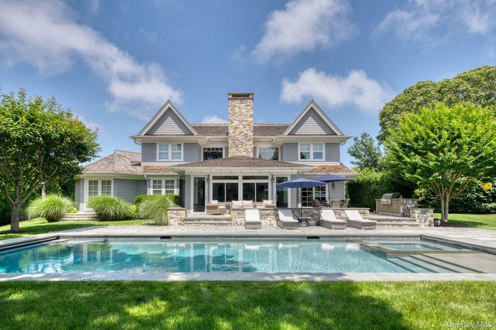 Rear view of property featuring exterior kitchen, a patio area, a chimney, a pool with connected hot tub, and a yard