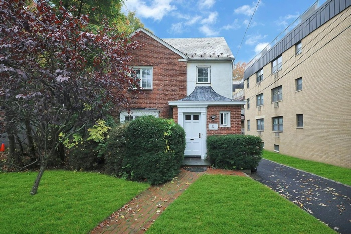 View of front of property featuring a high end roof, a front lawn, brick siding, and stucco siding