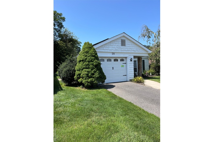 View of front of property featuring concrete driveway, a garage, and a front lawn