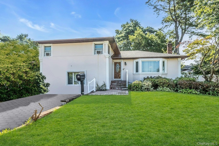 Split level home with a front lawn, stucco siding, and a chimney