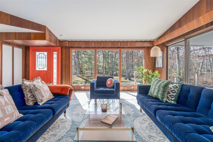 Living area featuring a healthy amount of sunlight, vaulted ceiling, and wooden walls