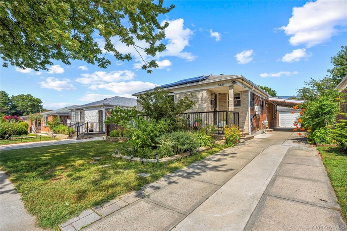 View of front facade featuring solar panels, brick siding, and concrete driveway