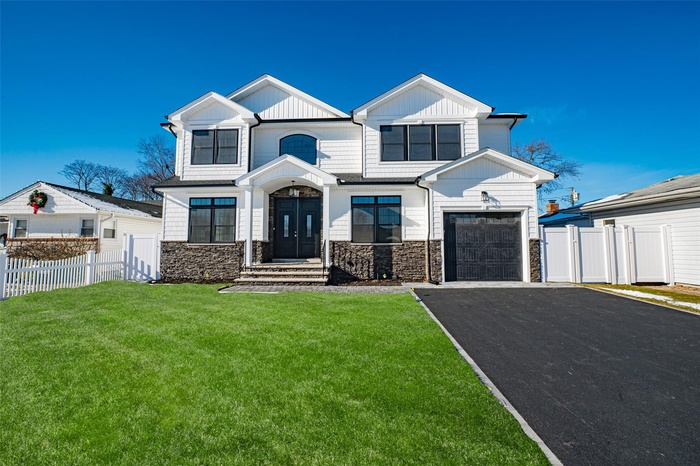 Modern farmhouse with a garage, aphalt driveway, a front yard, and fence