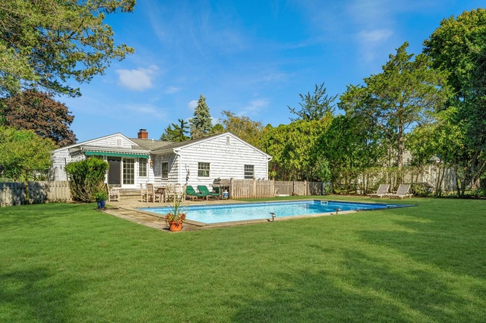 Back of property featuring a fenced backyard, a fenced in pool, and a lawn