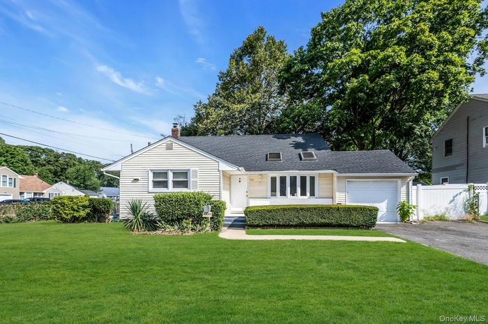 View of front of home featuring driveway, an attached garage, a chimney, and a shingled roof