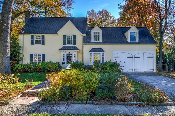 View of front of house with a chimney, roof with shingles, asphalt driveway, and stucco siding