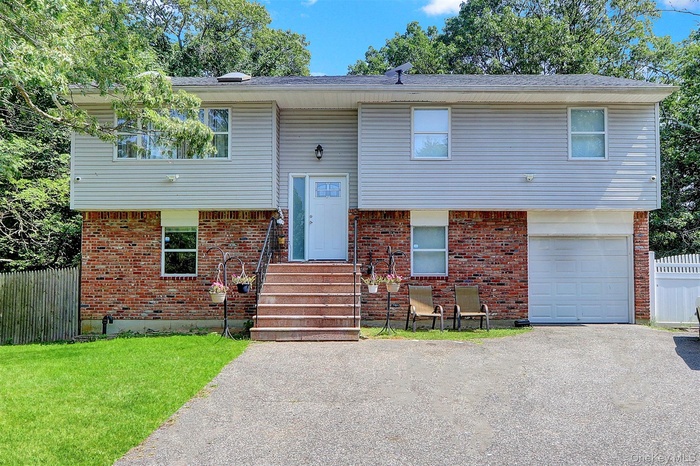 Raised ranch with an attached garage, asphalt driveway, brick siding, and entry steps