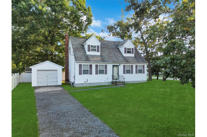 Cape cod home with an outdoor structure, driveway, a detached garage, a chimney, and a shingled roof