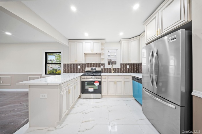 Kitchen with appliances with stainless steel finishes, a peninsula, open shelves, a sink, and light marble finish floors
