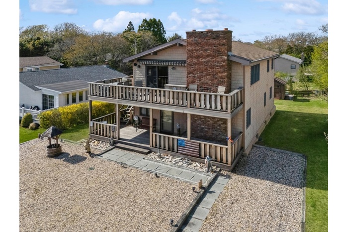 Back of house featuring a lawn, a chimney, and a deck