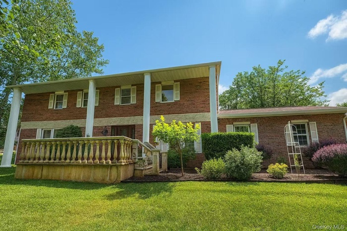 Front of property featuring brick siding, a yard, and covered porch