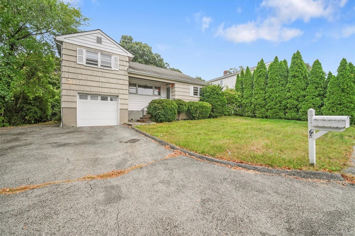 View of front of property with a front yard, driveway, and a garage