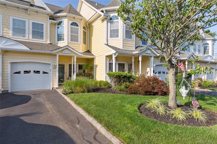 View of front of home with roof with shingles, an attached garage, a front yard, and asphalt driveway