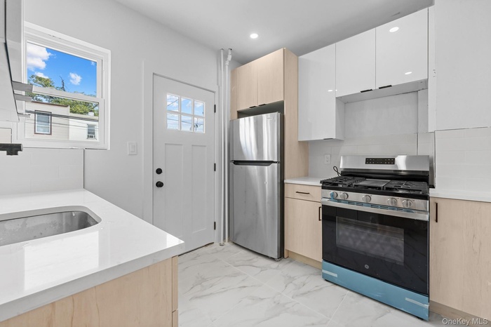 Kitchen featuring light brown cabinets, appliances with stainless steel finishes, light marble finish flooring, tasteful backsplash, and recessed ligh