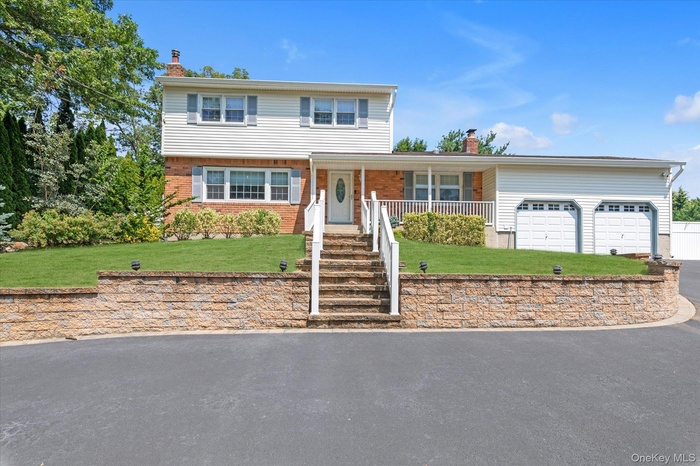 View of front of home with a chimney, a front lawn, covered porch, asphalt driveway, and brick siding