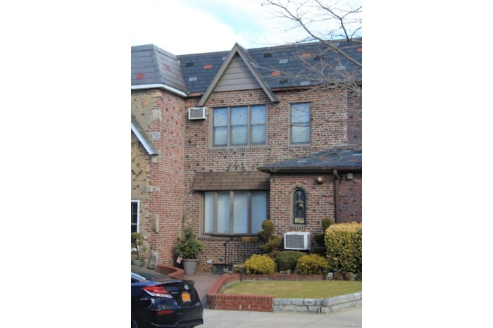 View of front of house featuring brick siding and a wall mounted AC