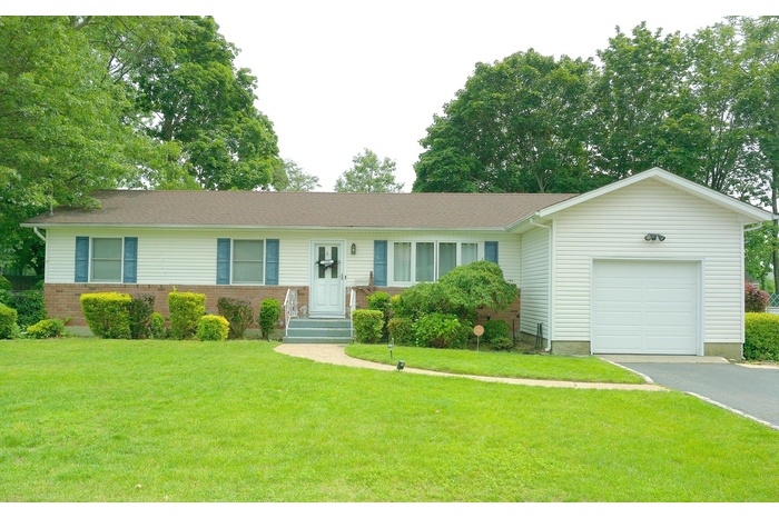 Ranch-style home featuring a garage, asphalt driveway, a front lawn, and brick siding