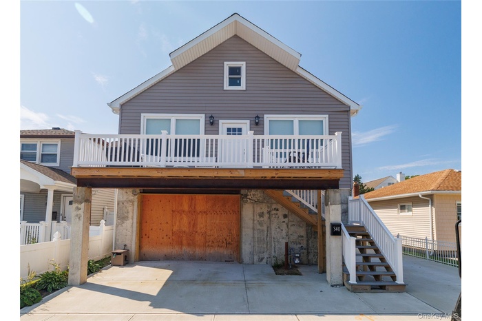 View of front of home featuring driveway, stairway, an attached garage, and a wooden deck