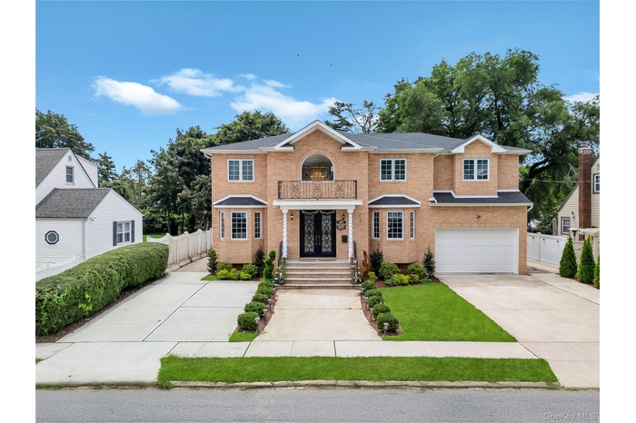 View of front of house featuring brick siding, concrete driveway, a balcony, and an attached garage