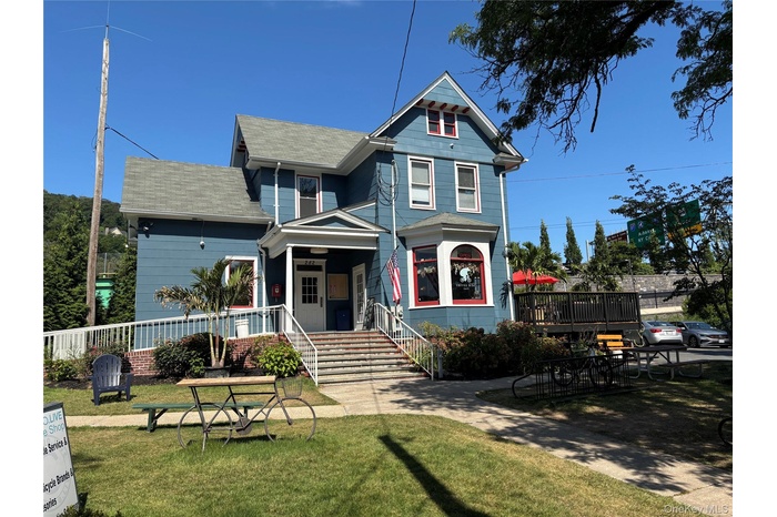 Victorian-style house featuring a shingled roof, a front yard, stairs, and covered porch
