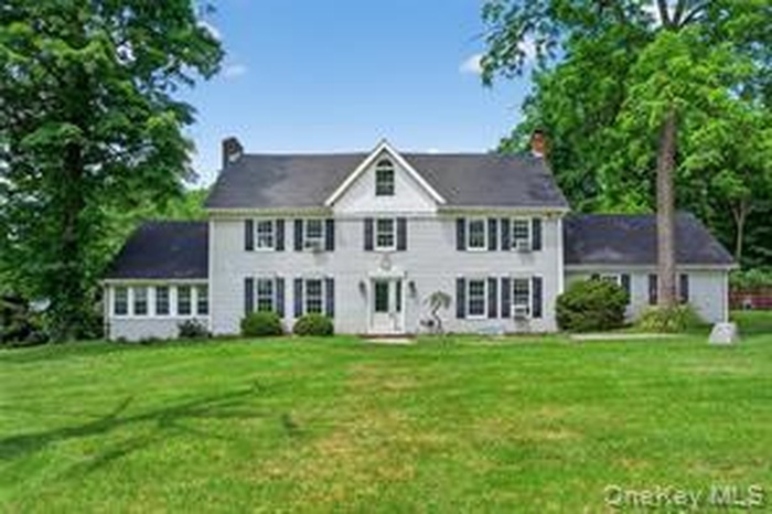 Colonial-style house with a front lawn and a chimney