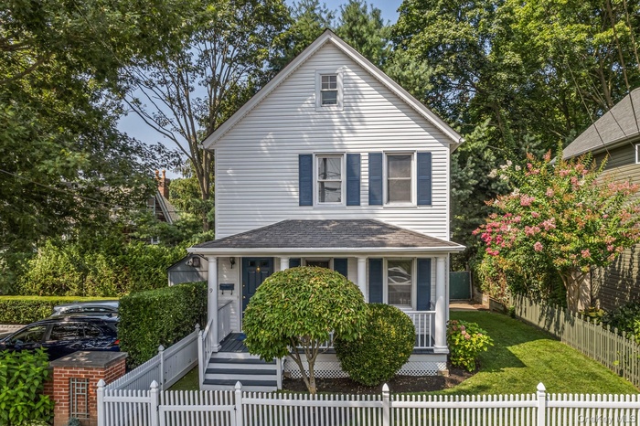 View of front of home with view of wooded area, roof with shingles, and a fenced front yard