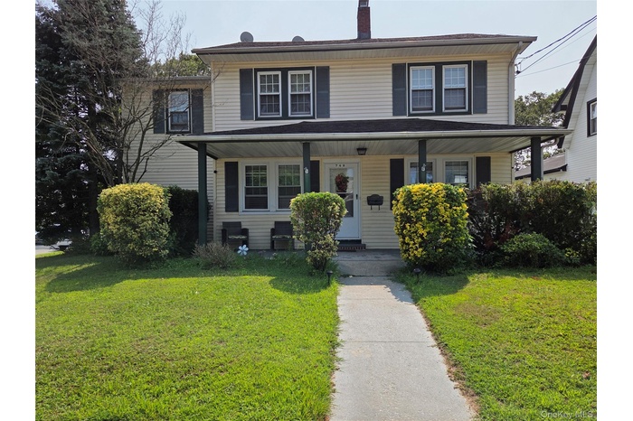 View of front of home with a front lawn, a porch, and a chimney