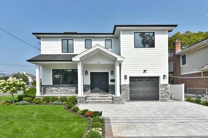 View of front of home with stone siding, an attached garage, and decorative driveway