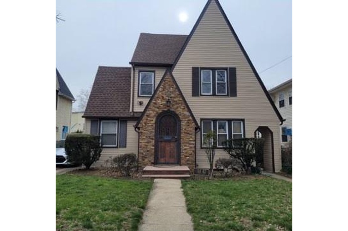 Tudor home with a front yard and stone siding