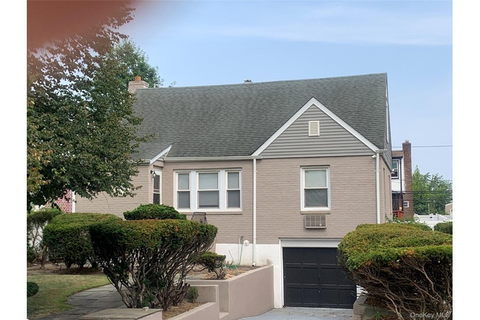 View of front facade with an attached garage, a chimney, roof with shingles, and driveway