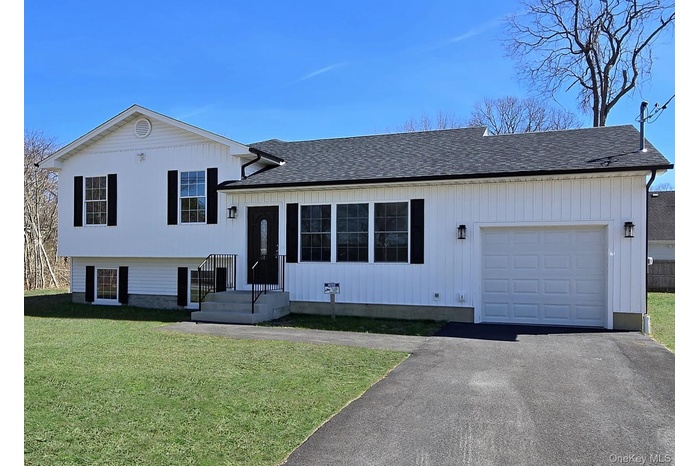 Tri-level home with a garage, a front yard, roof with shingles, and driveway
