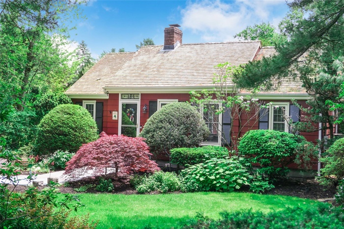 Cape cod-style house with a chimney and a front yard