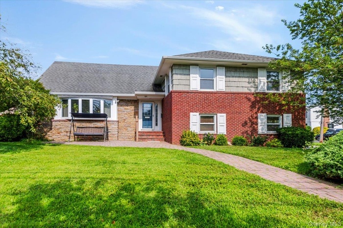 Split level home with a front lawn, brick siding, and entry steps
