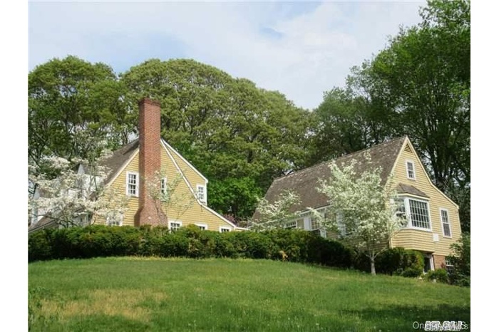 View of side of home featuring a chimney, a yard, and view of scattered trees