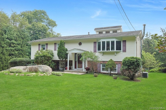 Bi-level home featuring a front lawn and brick siding