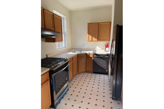 Kitchen featuring gas range, freestanding refrigerator, under cabinet range hood, dishwasher, and light flooring