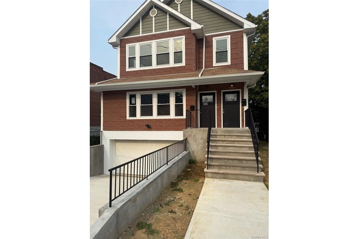 View of front of home featuring brick siding, an attached garage, a porch, stairway, and driveway